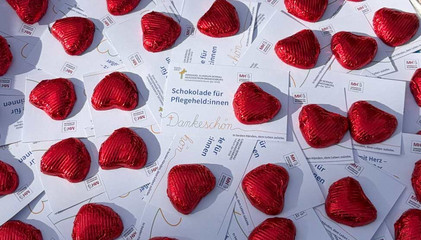 Zahlreiche rot verpackte Schokoherzen liegen um Dankeskarten mit der Aufschrift "Schokolade für Pflegeheld:innen" am Internationalen Tag der Pflegenden im Immanuel Klinikum Bernau Herzzentrum Brandenburg.