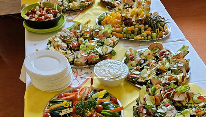 Ein reich gedecktes Buffet mit Obst, Fingerfood, Gemüse, belegten Schnittchen und weißen Tellern am Internationalen Tag der Pflegenden.