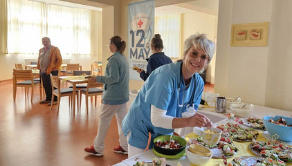Eine Pflegerin in blauer Funktionskleidung bedient sich an einem Buffet zum Internationalen Tag der Pflegenden im Immanuel Krankenhaus Berlin in Berlin-Wannsee.